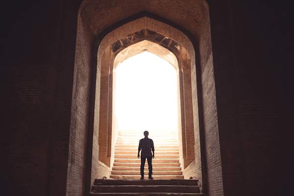 man going up stairs into light