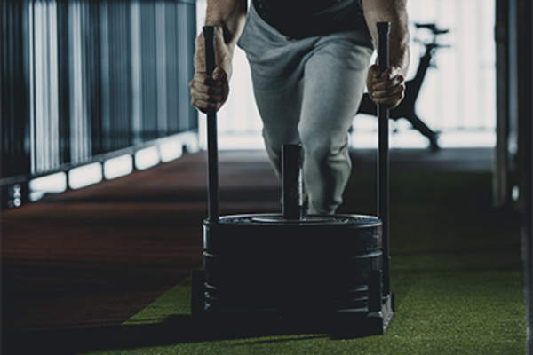 Man pushing a weighted sled at the gym.