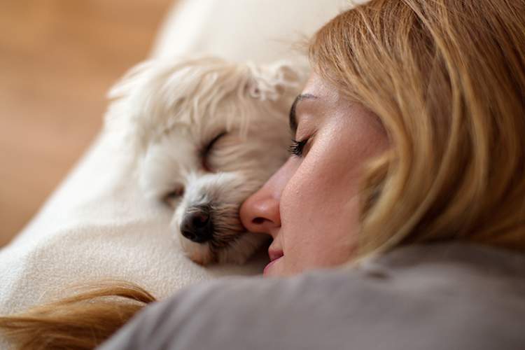 Woman getting some sleep with her small white dog.