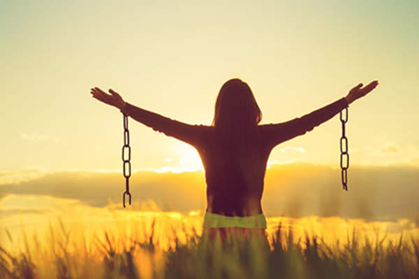 Woman free with arms raised, broken chains.