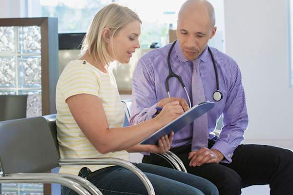 Woman with doctor filling out medical form.