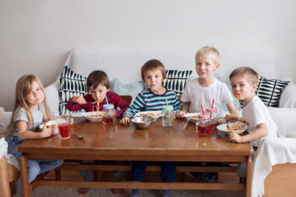Kids eating spaghetti at coffee table.