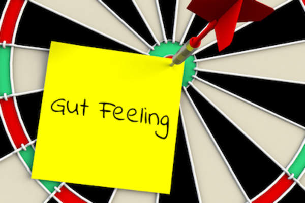 Dart board with sticky note, gut feeling, dart in bullseye.