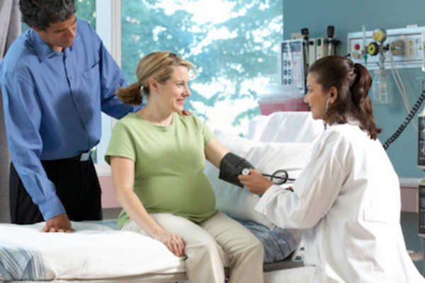 Husband and pregnant wife at doctors office.