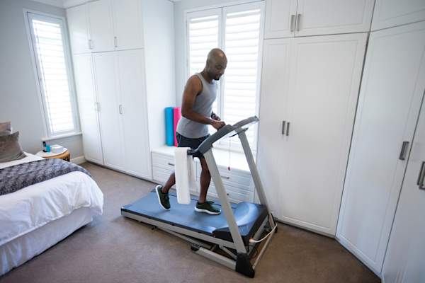 Mid section of man using smart watch while exercising on treadmill