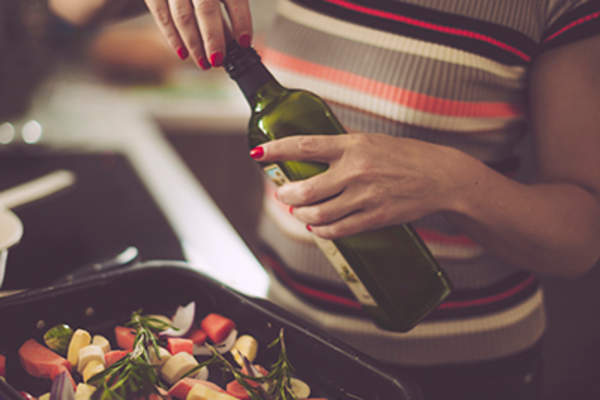 Woman using olive oil while cooking.