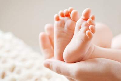 A woman holding a newborn baby's feet.