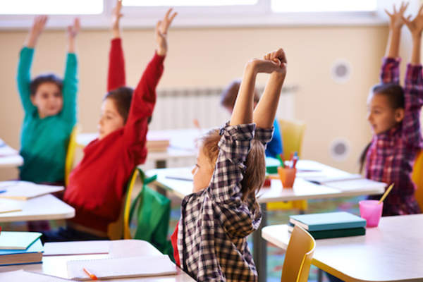 Young students stretching at their desks.