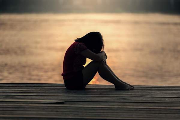 sad woman on dock at sunset