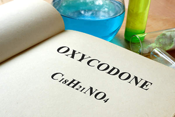 Book with oxycodone and test tubes on a table.