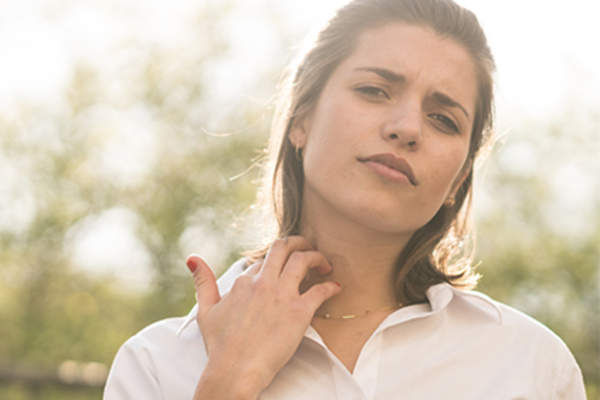 Young woman scratching an itch on her neck.