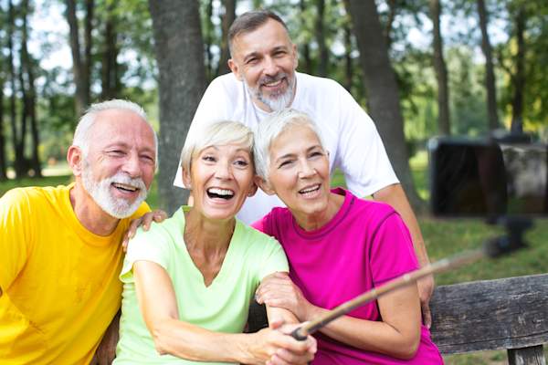 Group of older friends posing for group selfie.