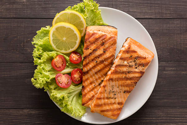 Grilled salmon with lemon, tomato on wooden background