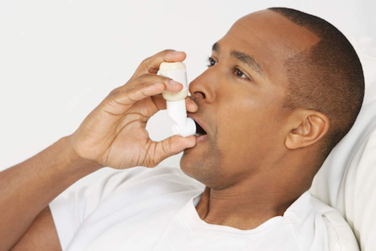 African american man with inhaler during asthma attack.