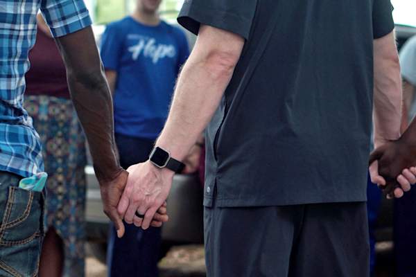 support group standing in circle holding hands