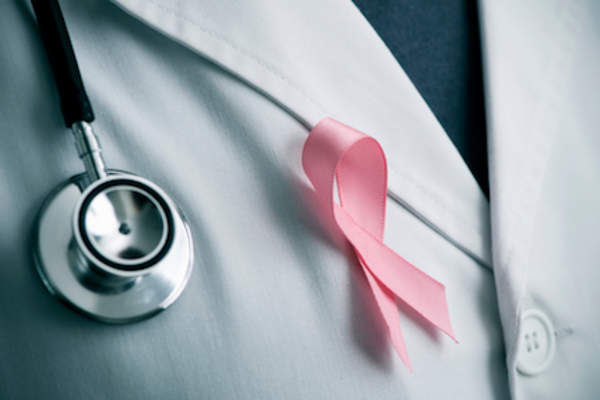 Pink breast cancer awareness ribbon on doctors white coat.