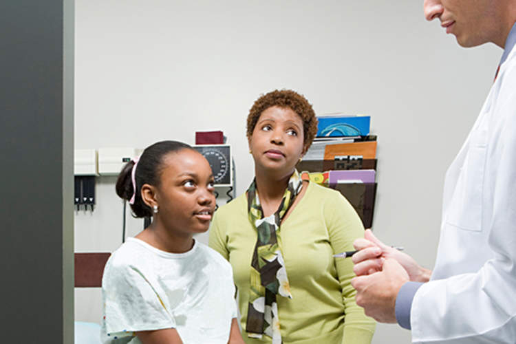 Mother and young daughter listening to doctor.
