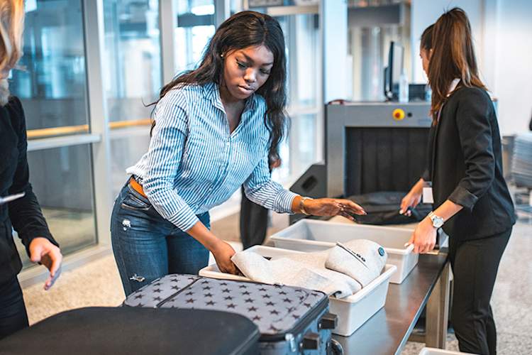Woman going through luggage check at airport security.