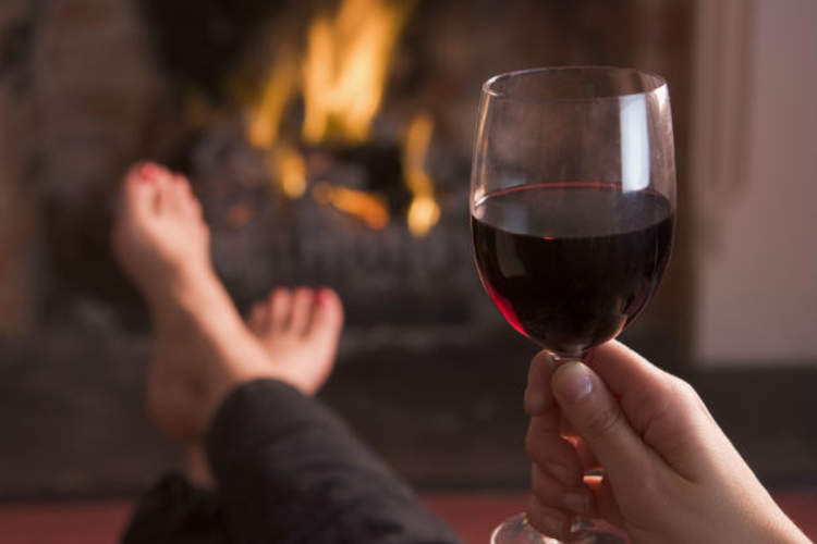 woman drinking wine in front of fireplace