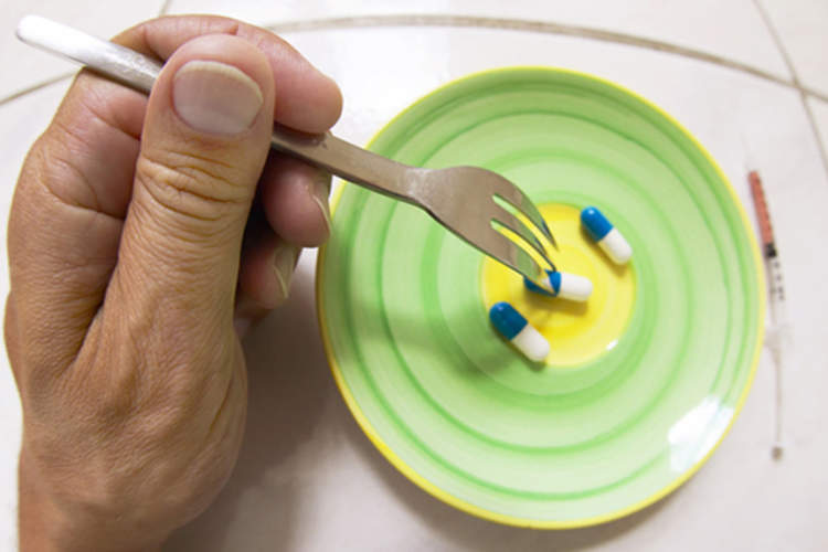 A person eats a plate of pills with a fork.