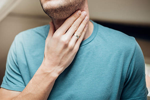 Man with acid reflux holding his throat.
