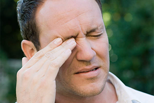 Man rubbing his irritated eye.