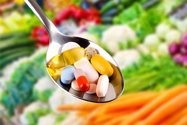 Colorful diet supplements in spoon with fresh vegetables.