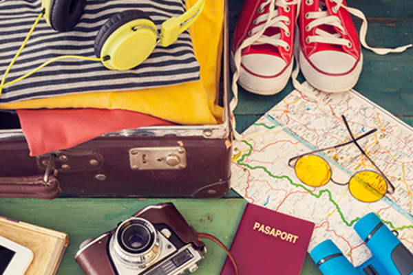 Packing suitcase with passport, camera, clothing, and map