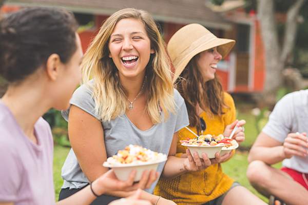 Happy friends eating at a party together outside.