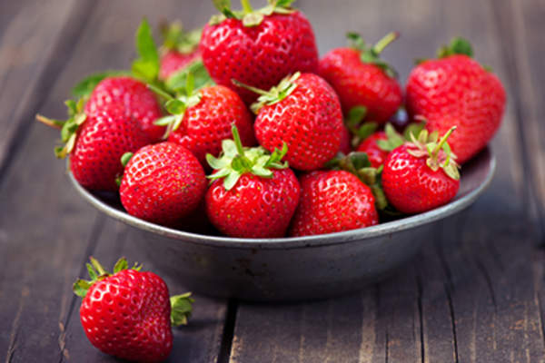 Strawberries in a bowl on rustic wood