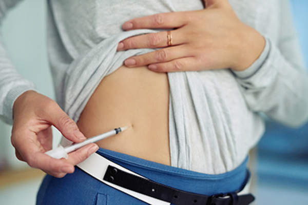 Diabetic woman giving herself an insulin injection.