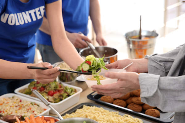 Volunteer serving food at soup kitchen.