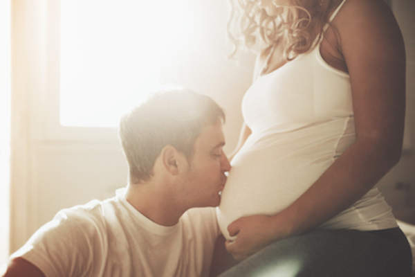 Husband kissing pregnant wife's belly.