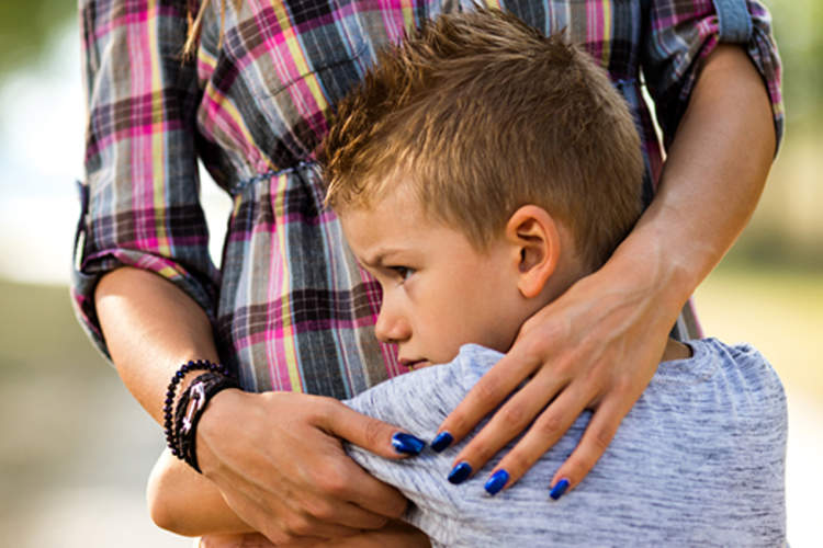 Boy with anxiety hugging mother.