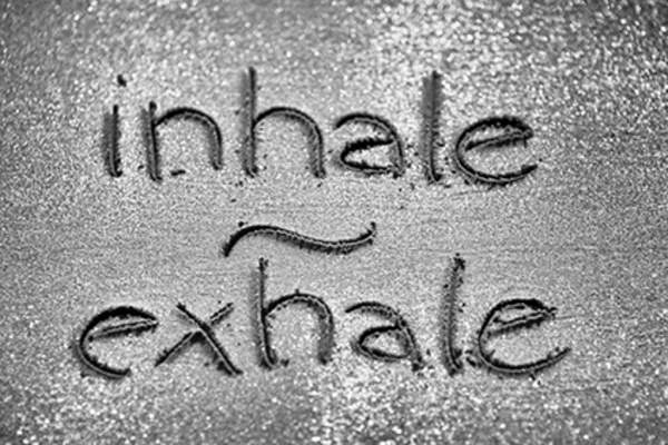 Inhale and exhale written in sand.