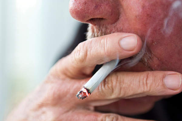 Older man with mustache smoking cigarette.