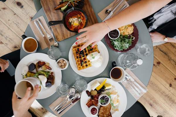 women at brunch, hand reaching towards waffle