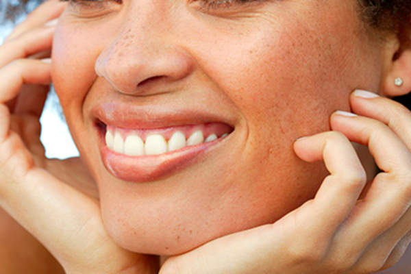Woman curling her fingers against her cheeks.