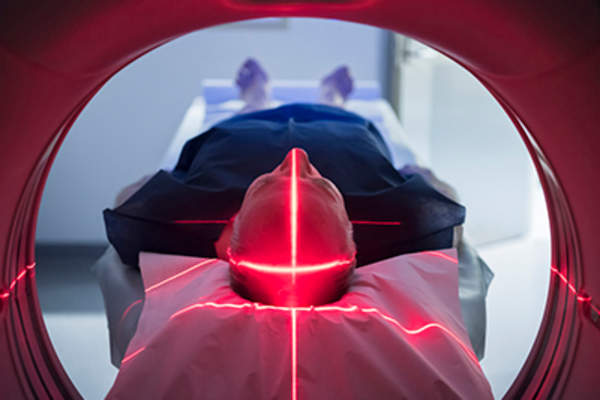 Man in medical scanner with red lights.