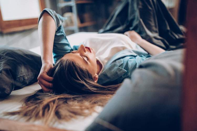 Teenage girl lying on her bed with PMS symptoms.