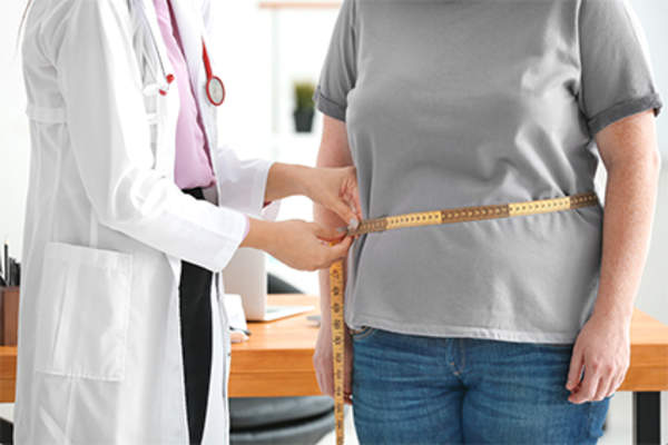Doctor measuring waist size of overweight woman.