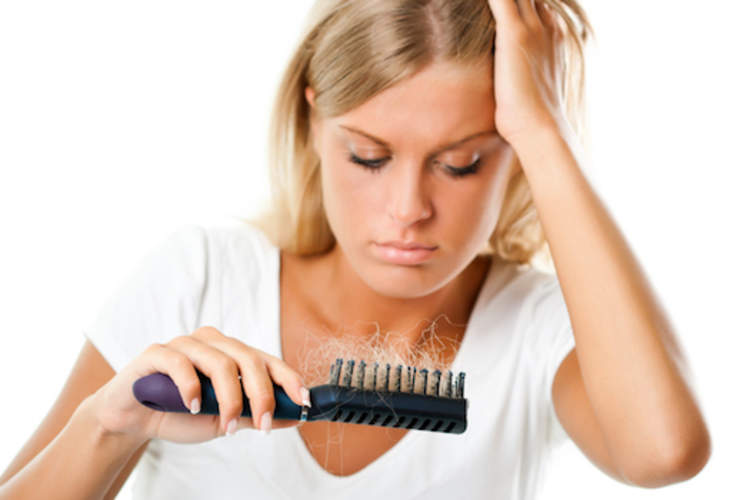 Woman staring at all the hair caught in her brush.