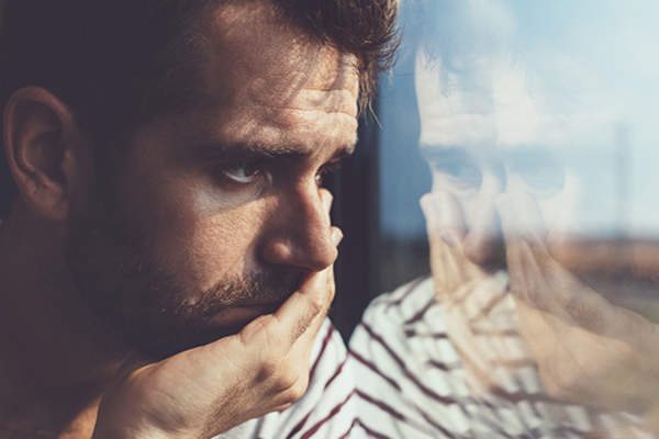 Depressed man looking out window.