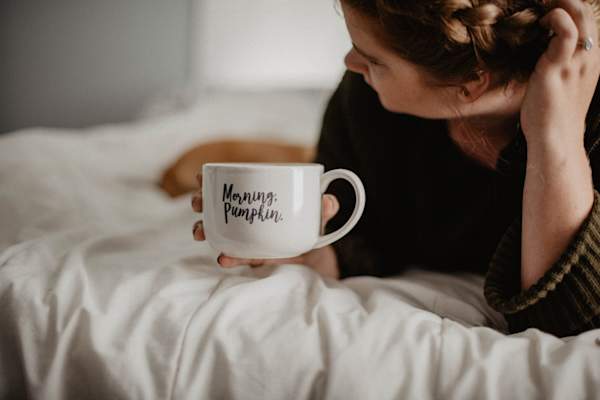 woman in bed holding mug that reads "morning, pumpkin."
