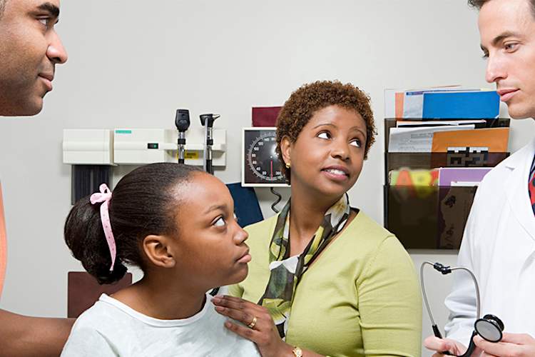 Teen girl talking to her doctor with her parents.