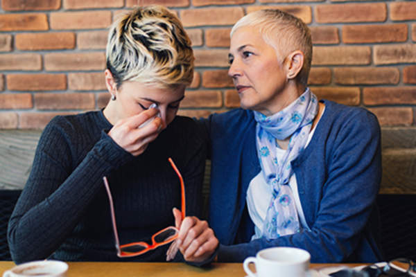 Mother comforting young adult daughter who is upset.