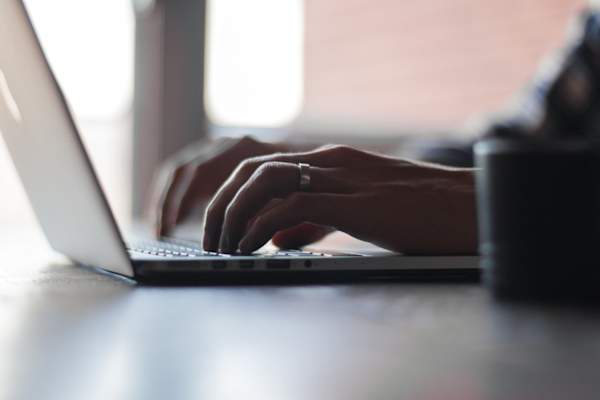 man's hands typing on laptop