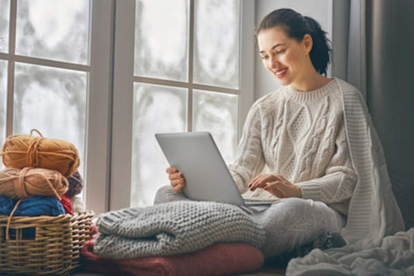 Woman on computer in front of window.