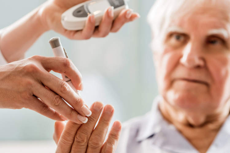 A nurse uses a blood glucose monitor to check a man's blood sugar levels.