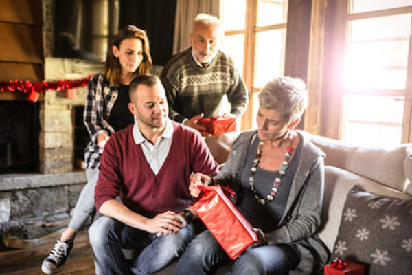 Mother opening present while family watches